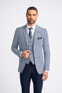 Homem vestindo um terno xadrez azul claro com camisa branca e gravata estampada sobre um fundo branco.