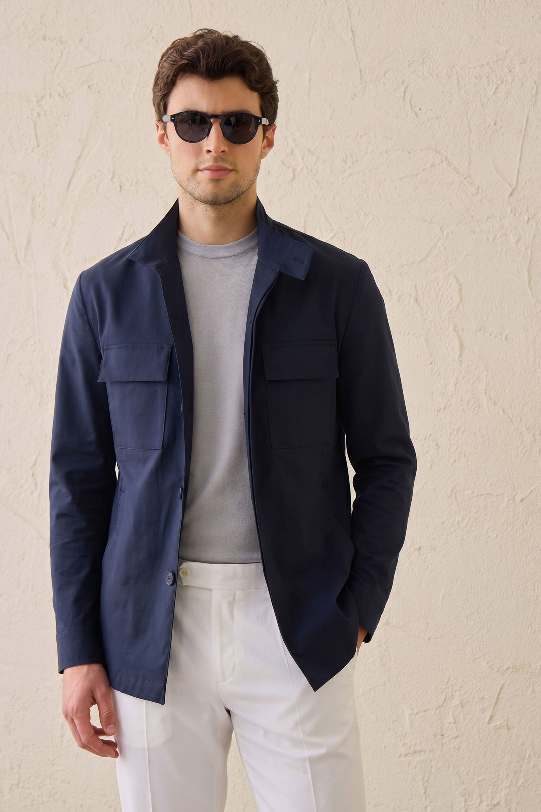 Conjunto masculino elegante e casual com jaqueta safari em mistura de algodão azul-marinho e calça branca.
