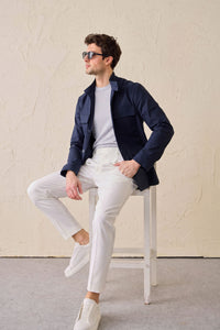Conjunto masculino elegante e casual com jaqueta safari em mistura de algodão azul-marinho e calça branca.