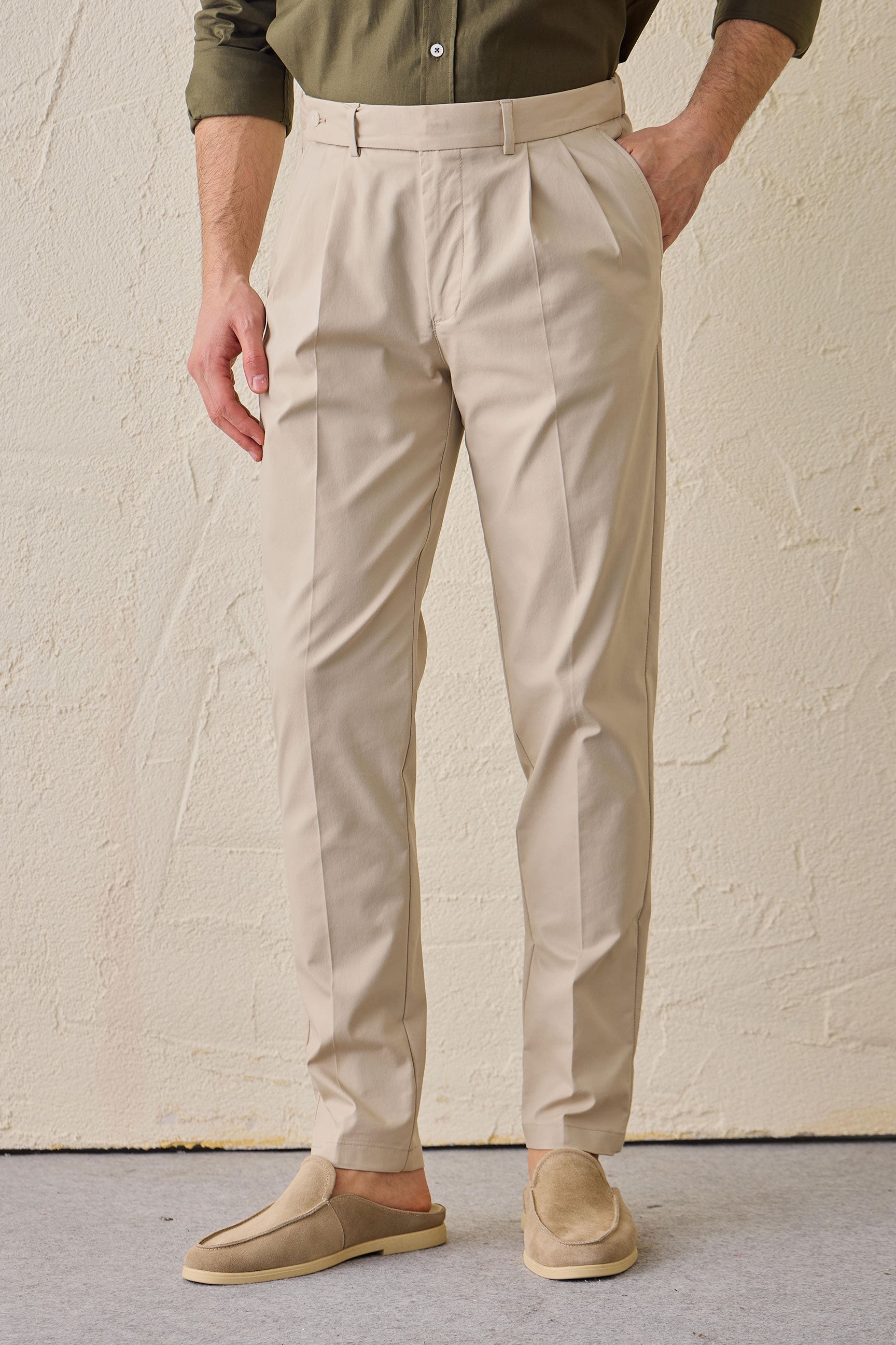 Conjunto masculino casual elegante com jaqueta safari verde-sálvia em mistura de algodão e calça bege.