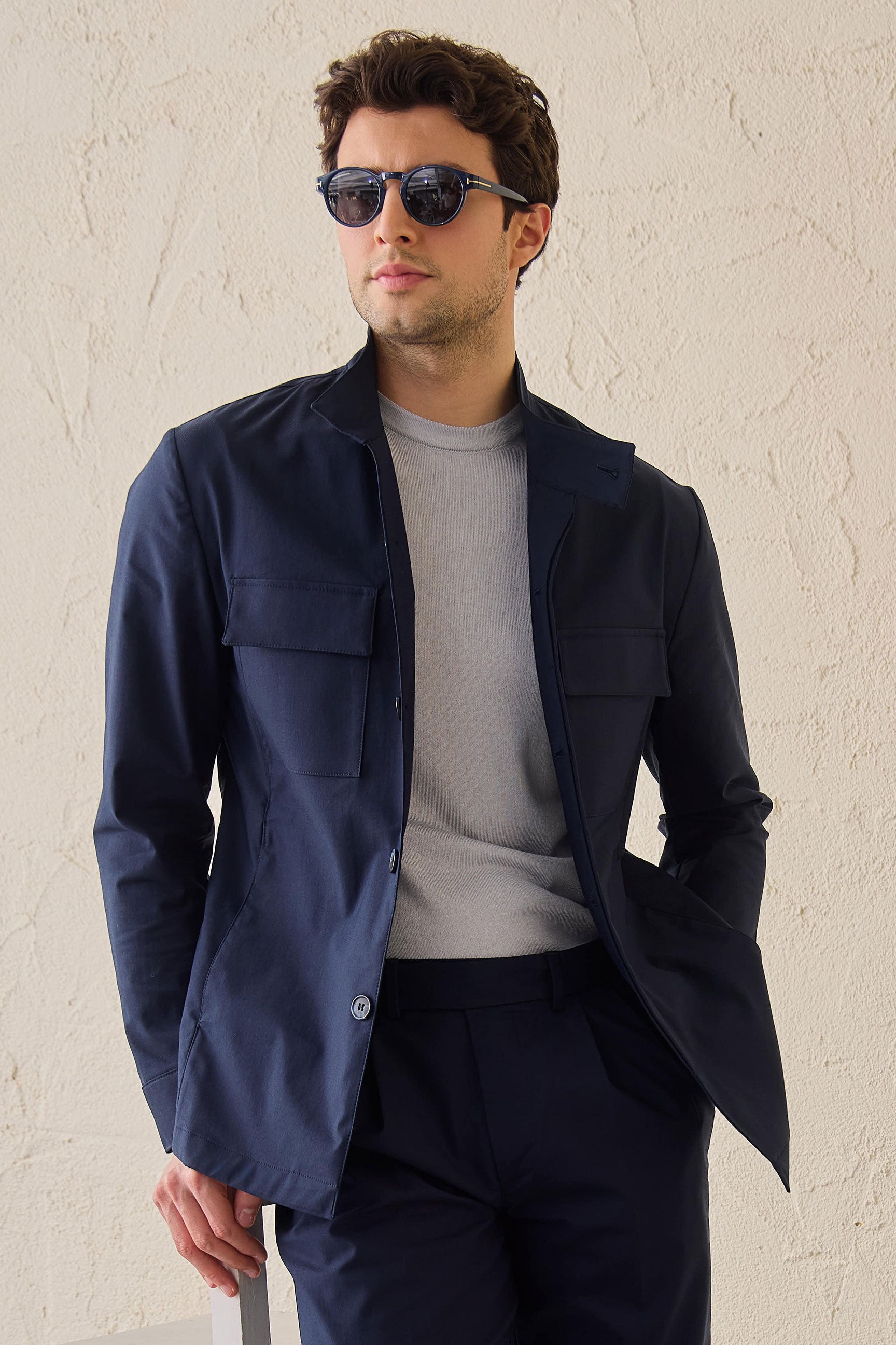Terno masculino azul-marinho estilo safari, duas peças, elegante e casual, com gola alta e tecido elástico.