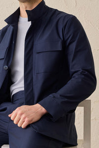 Terno masculino azul-marinho estilo safari, duas peças, elegante e casual, com gola alta e tecido elástico.