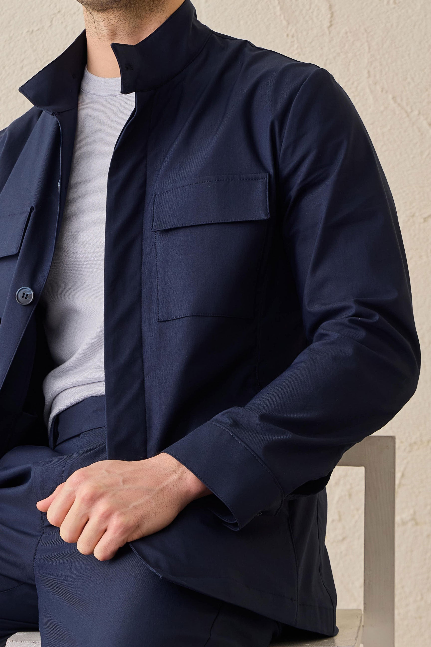 Terno masculino azul-marinho estilo safari, duas peças, elegante e casual, com gola alta e tecido elástico.