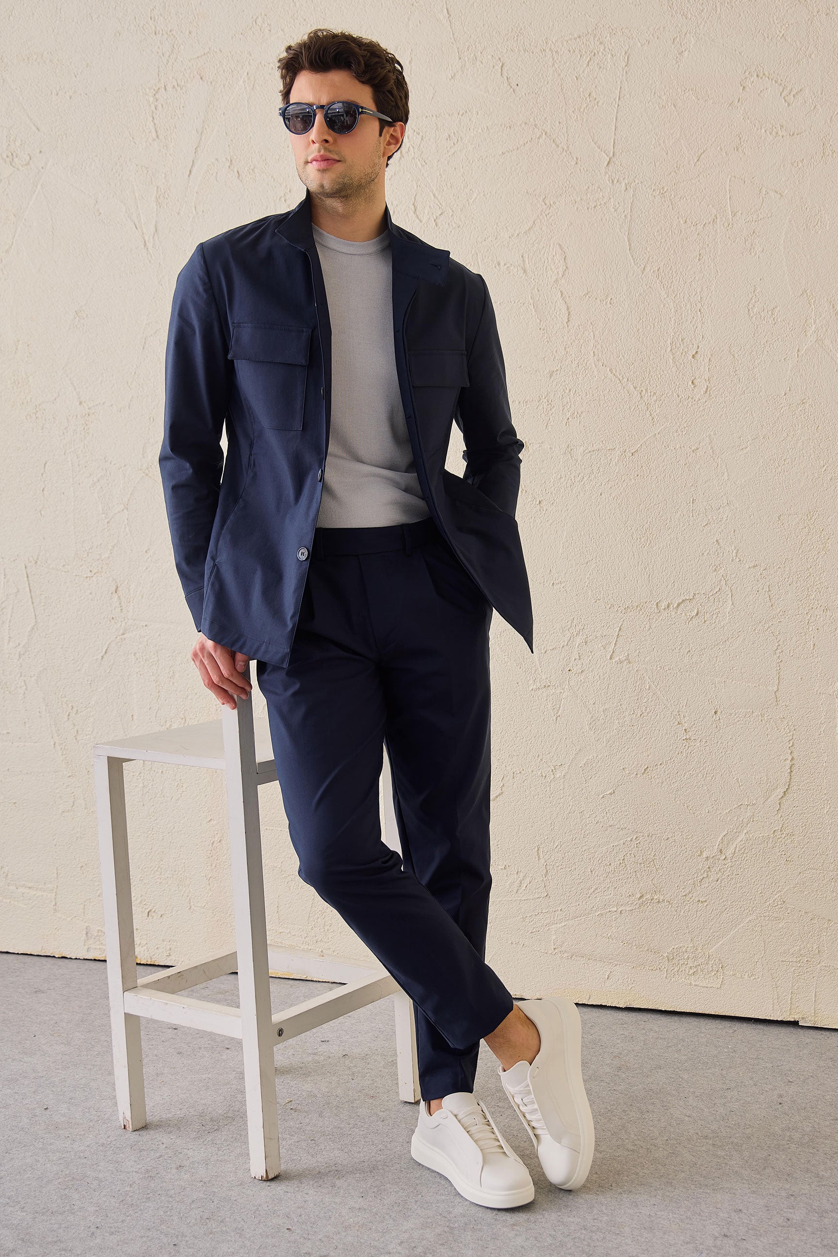 Terno masculino azul-marinho estilo safari, duas peças, elegante e casual, com gola alta e tecido elástico.
