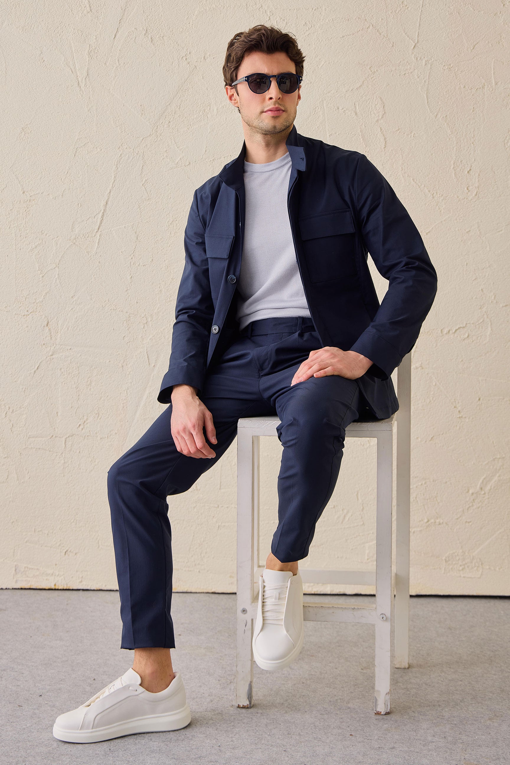 Terno masculino azul-marinho estilo safari, duas peças, elegante e casual, com gola alta e tecido elástico.