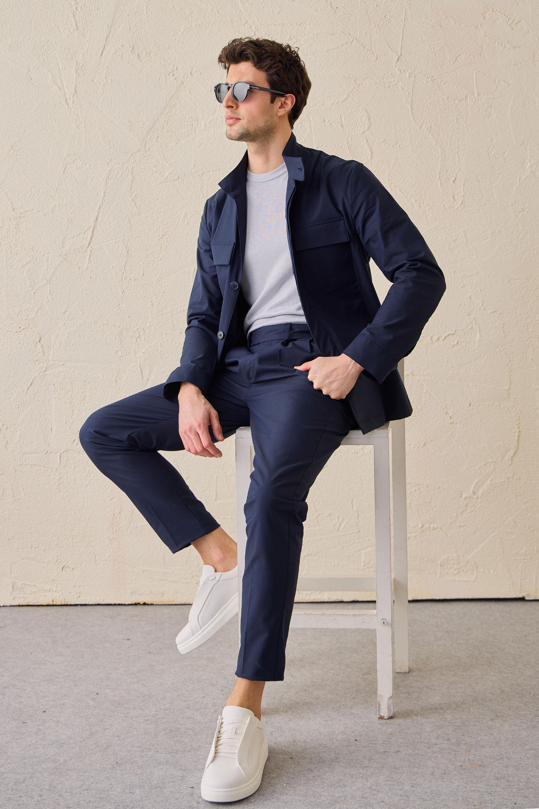 Terno masculino azul-marinho estilo safari, duas peças, elegante e casual, com gola alta e tecido elástico.