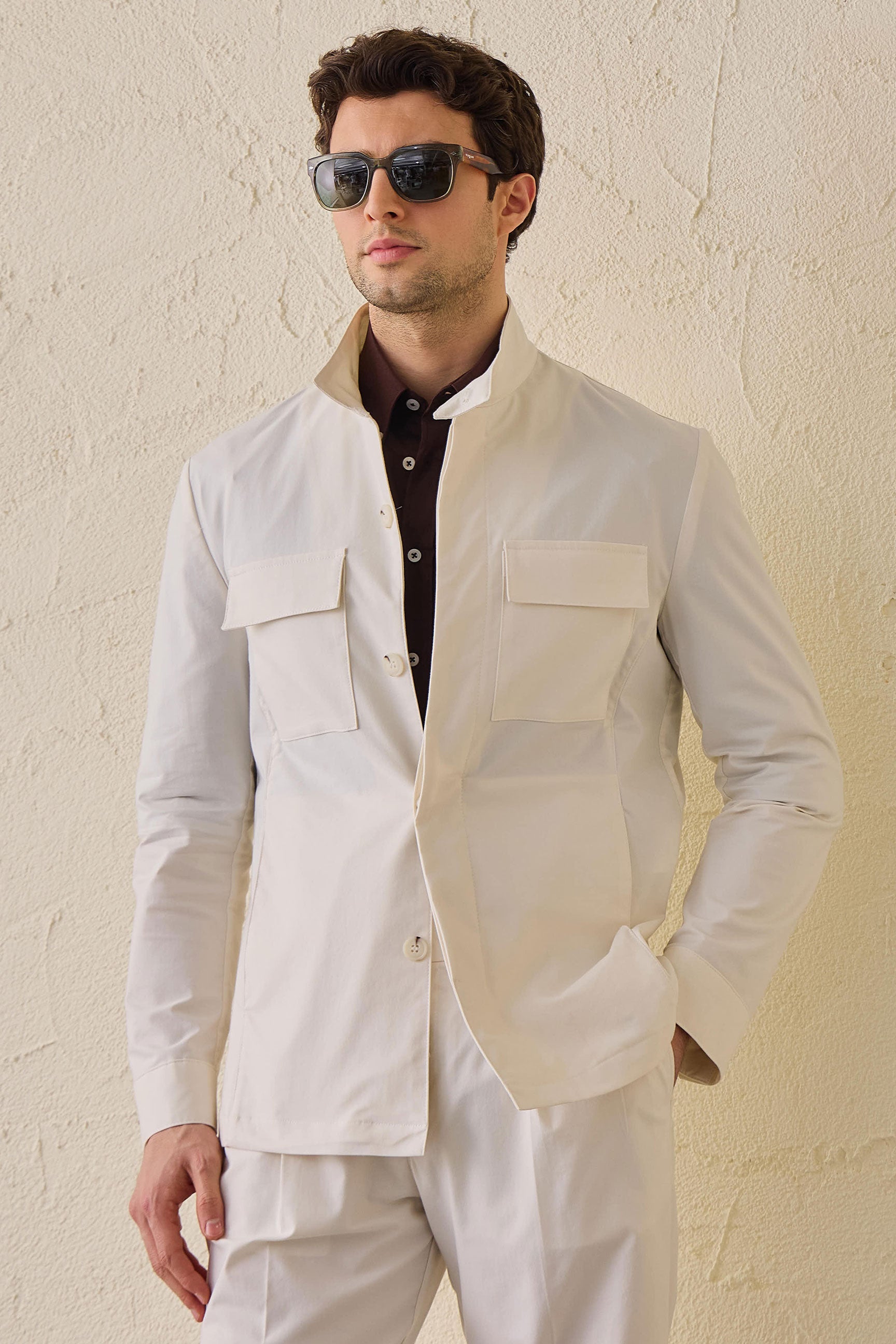 Terno masculino branco de duas peças, estilo safari, com gola alta e tecido elástico.