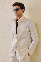 Terno masculino branco de duas peças, estilo safari, com gola alta e tecido elástico.