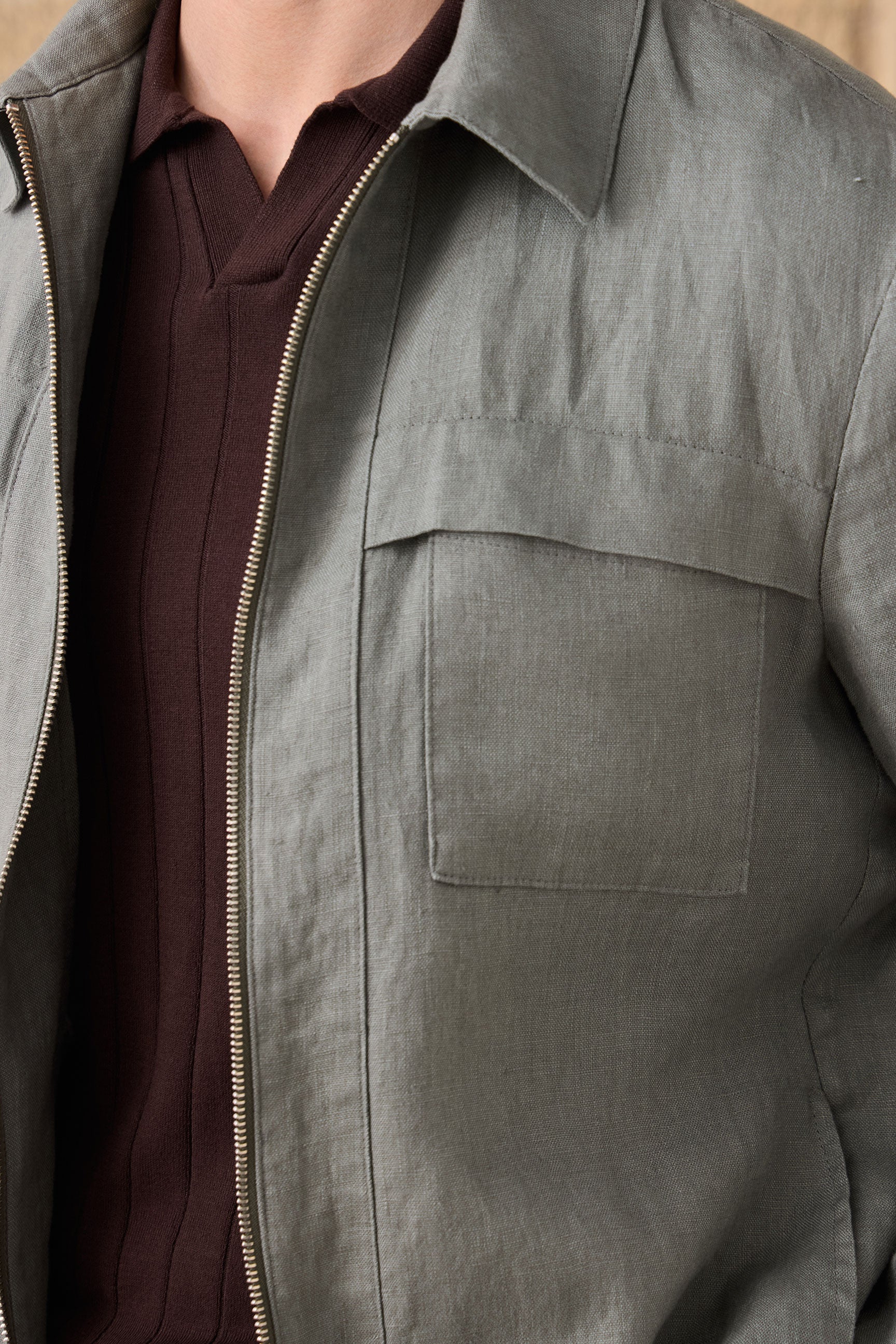 Conjunto masculino de jaqueta de linho verde-sálvia com zíper e calça marrom, look casual elegante para o verão.