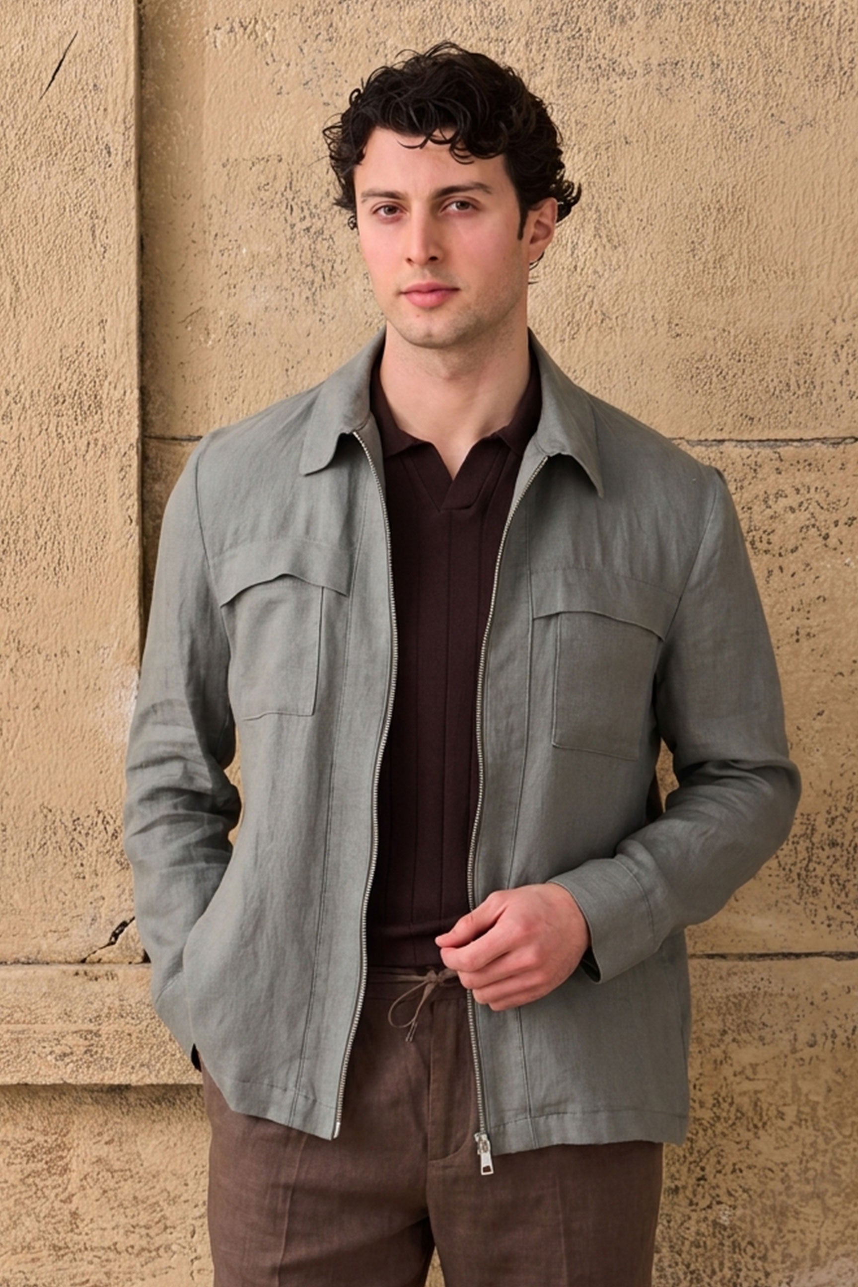 Conjunto masculino de jaqueta de linho verde-sálvia com zíper e calça marrom, look casual elegante para o verão.