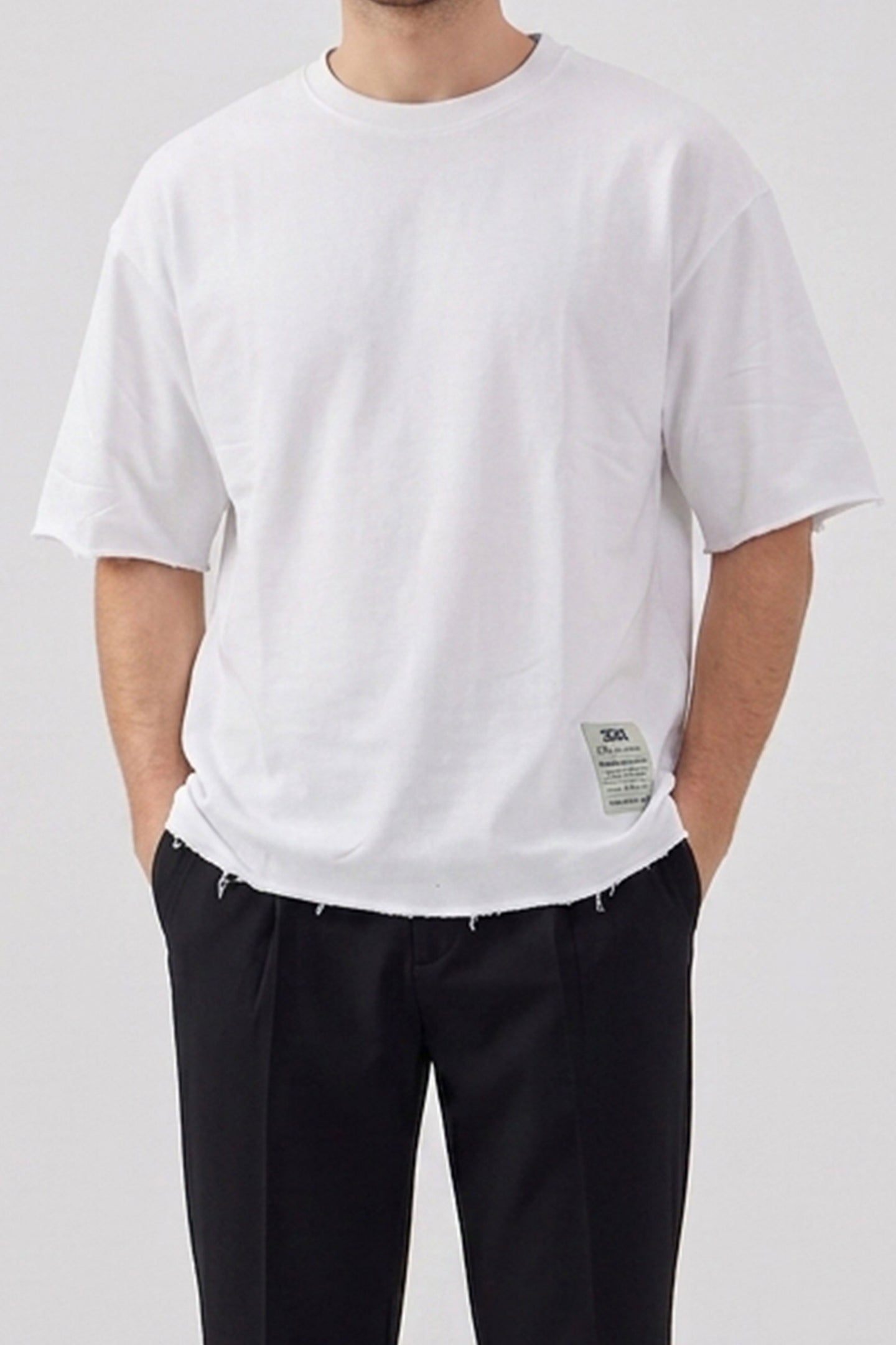 Camiseta masculina branca de corte relaxado com barra desfiada e gola redonda em mistura de algodão.