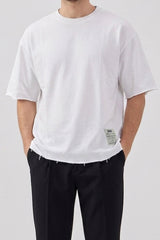 Camiseta masculina branca de corte relaxado com barra desfiada e gola redonda em mistura de algodão.
