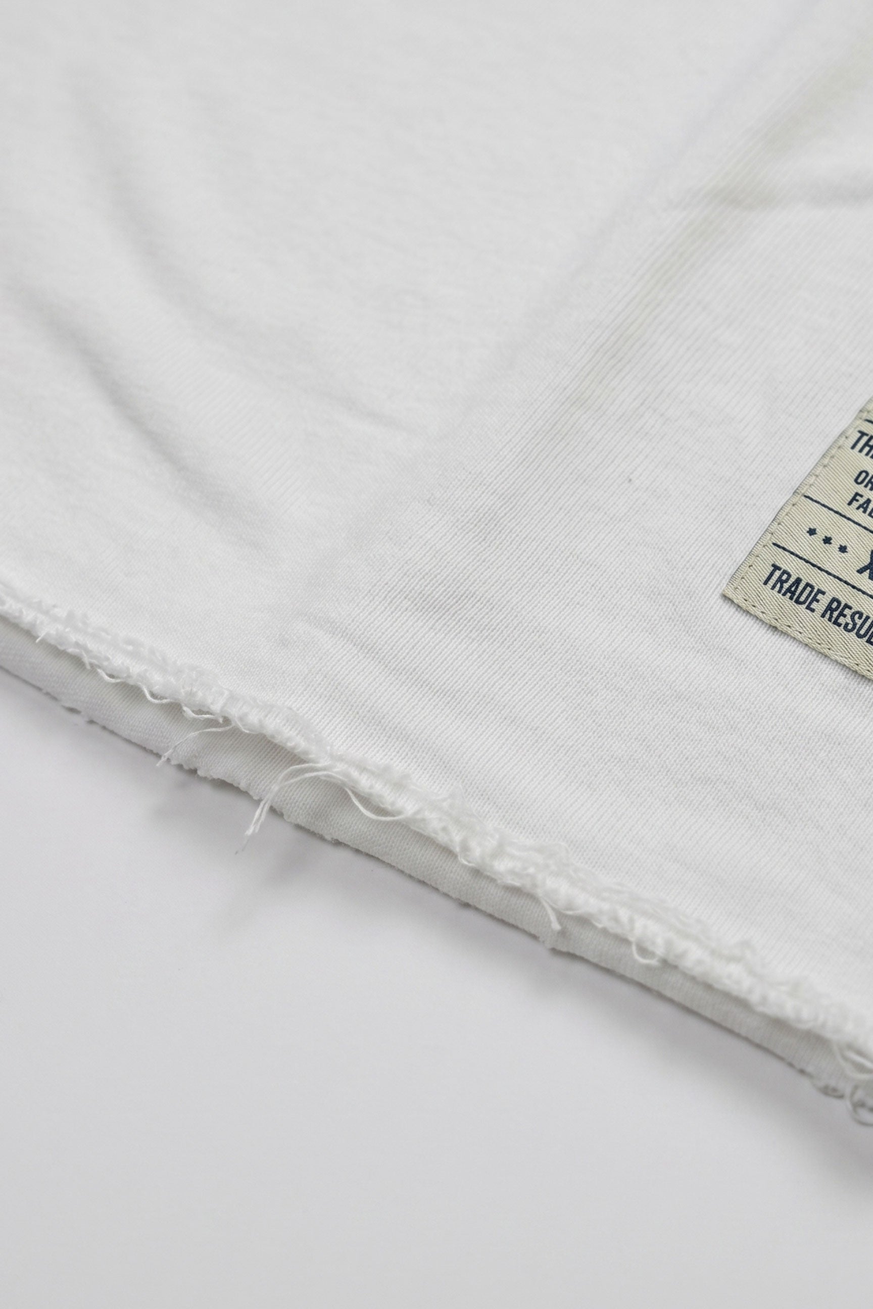 Camiseta masculina branca de corte relaxado com barra desfiada e gola redonda em mistura de algodão.